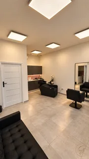 Strefa fryzjerska z czarnymi fotelami i wyposażeniem salonu.